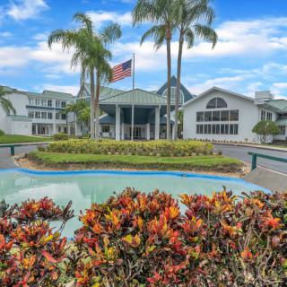 A welcoming hotel entrance surrounded by lush tropical landscaping and palm trees.
