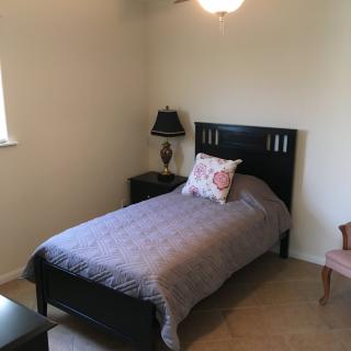 A minimalist bedroom with a single bed, side table, and lamp.