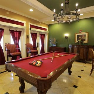 A luxurious billiard room with a red felt pool table and elegant decor.