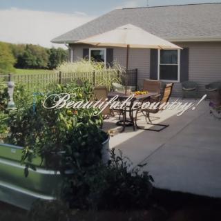 A beautiful country patio with outdoor seating and a lush garden.