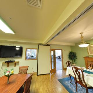 A cozy dining room with elegant furniture and a television on the wall.