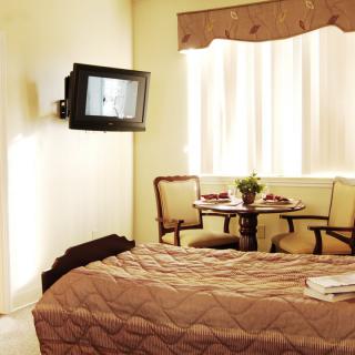 A cozy bedroom with a mounted television, dining table, and comfortable bedding.