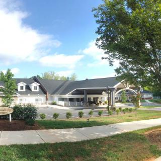 A modern residential home with a well-maintained lawn and clear blue sky.