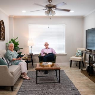 An elderly couple sitting in a cozy, well-decorated living room with modern furnishings.