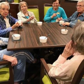 A group of elderly people enjoying ice cream together indoors.