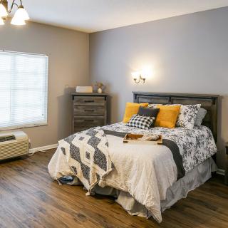 A cozy bedroom with a neatly made bed and bright natural light.