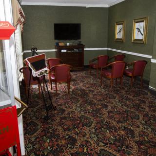 A cozy room with red chairs, a wall-mounted television, and decorative artwork on green walls.