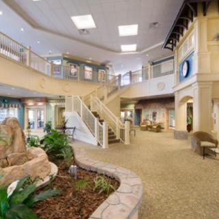 A spacious and welcoming lobby featuring a central staircase and indoor greenery.