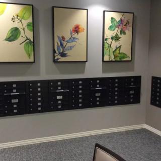 A lobby area featuring a row of mailboxes beneath botanical artwork.