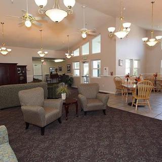 A spacious community living area with armchairs, tables, and ceiling lights.