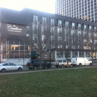 A view of a hotel building with cars parked in front during the day.