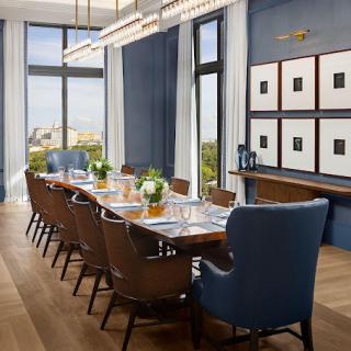 A beautifully designed dining room with a large table, elegant chairs, and decor elements such as artwork and expansive windows.