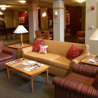 A cozy lobby area with a sofa, armchairs, and coffee table under warm lighting.