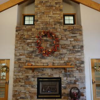 A cozy living room featuring a stone fireplace adorned with a seasonal wreath and wooden beams enhancing the rustic charm.