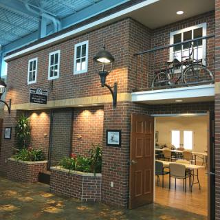 A charming brick building with bicycles on the balcony, featuring indoor greenery and warm lighting.