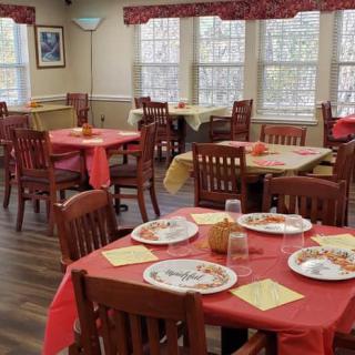 A cozy dining room with red tablecloths and set tables, ready for guests.