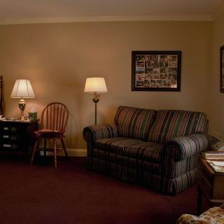 A cozy living room featuring a striped sofa, wooden chair, and lamps with warm lighting.