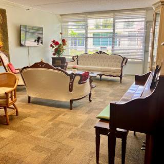 A stylish living room featuring elegant furniture and a grand piano, bathed in natural light.