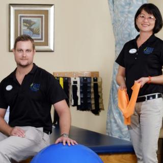 Two therapists in a clinic setting with exercise equipment.