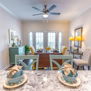 A modern dining room with a well-set table, featuring elegant decor and ample natural light.