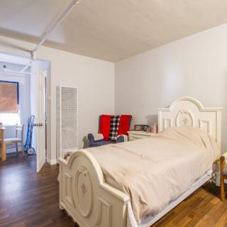 A minimalist bedroom with a single bed and wood flooring.