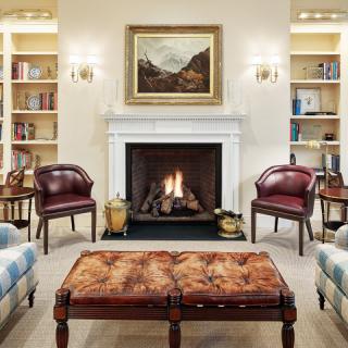 A cozy living room features a fireplace, bookshelves, and comfortable seating.
