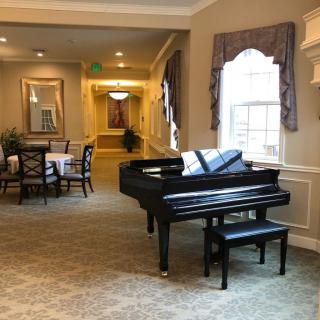 A cozy living and dining area with a grand piano and elegant furnishings.