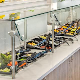 A well-stocked salad bar with a variety of fresh vegetables and toppings.