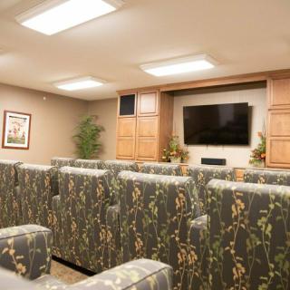 A cozy home theater room with patterned seating facing a large television.