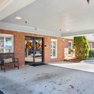 A welcoming entrance featuring a brick facade, decorative door wreaths, and a comfortable bench.