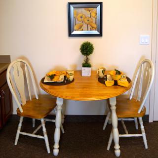 A cozy dining setup featuring a round wooden table with two chairs, decorated for a casual meal.