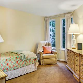 A cozy bedroom with a comfortable bed, armchair, and warm lighting.