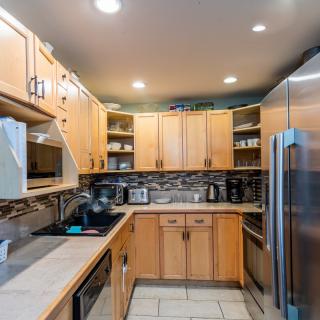 A modern kitchen with wooden cabinets, stainless steel appliances, and ample lighting.