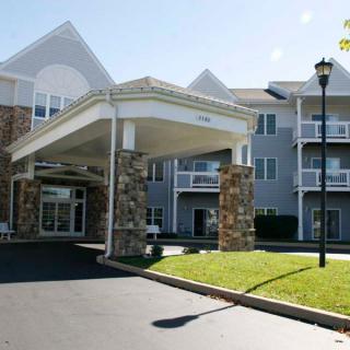 A modern residential building with a grand entrance and balconies on a sunny day.