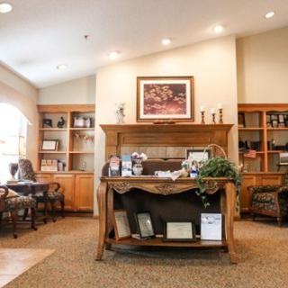 A welcoming office reception area with a wooden desk, bookshelves, and cozy lighting.
