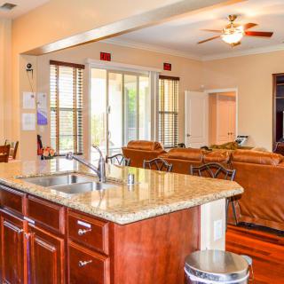 A spacious open floor plan kitchen and living area with granite countertops, wooden cabinets, and abundant natural light.