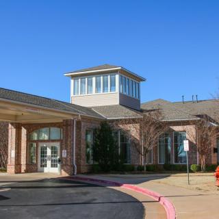 A modern building with a prominent entrance and large windows under a clear blue sky.