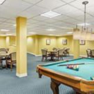 A spacious game room featuring a pool table and multiple seating areas.