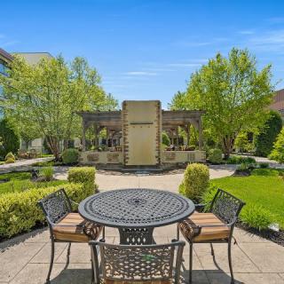 A tranquil garden patio with a metal table and chairs surrounded by lush greenery.
