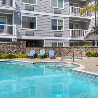 A modern apartment complex with a swimming pool and sun loungers.