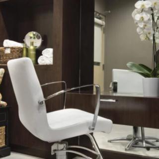 A modern salon interior featuring a white chair, a mirror, and elegant decor.