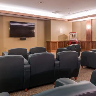 A modern theater room with comfortable seating and a large screen.