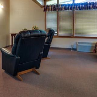 A cozy living room featuring reclining chairs and window blinds.