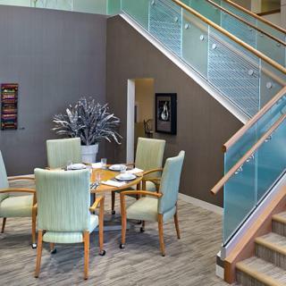 Modern dining area with a table, chairs, and art under a staircase.