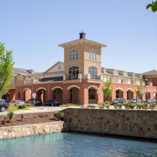 A modern commercial building with a water feature and lush landscaping.