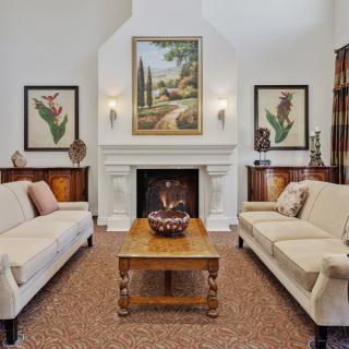 A traditionally styled living room featuring two sofas, a central fireplace adorned with art, and a wooden coffee table.