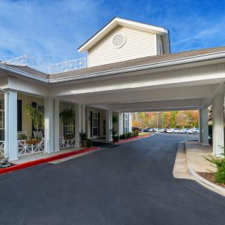An exterior view of a building entrance with a covered driveway and clear blue skies.