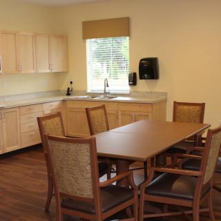 A modern kitchen and dining area with a table, chairs, cabinets, and a sink.