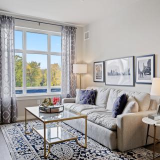 A beautifully decorated living room with a comfortable sofa, stylish coffee table, and ample natural light from the large window.