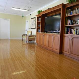 A spacious and inviting interior room featuring a wooden floor, a television set, and an organized bookshelf.